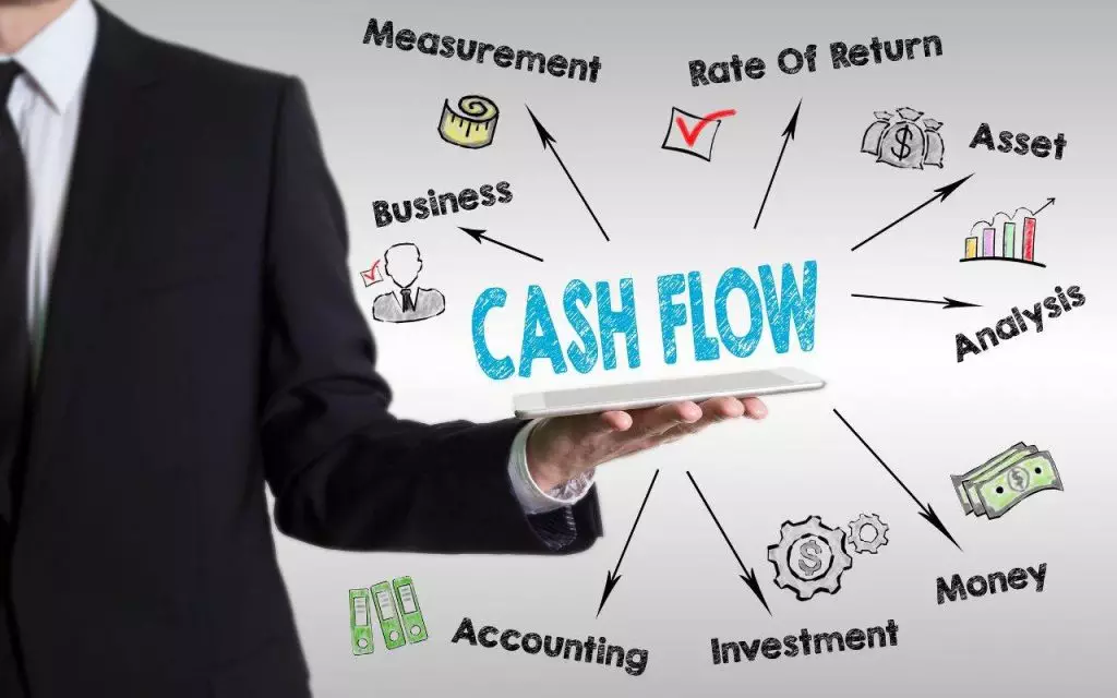 A businessman holding a tablet displaying cash flow information, addressing accounting pain points for small businesses.